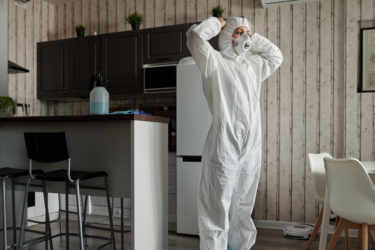 Personne en équipement de protection debout dans une cuisine moderne en journée.
